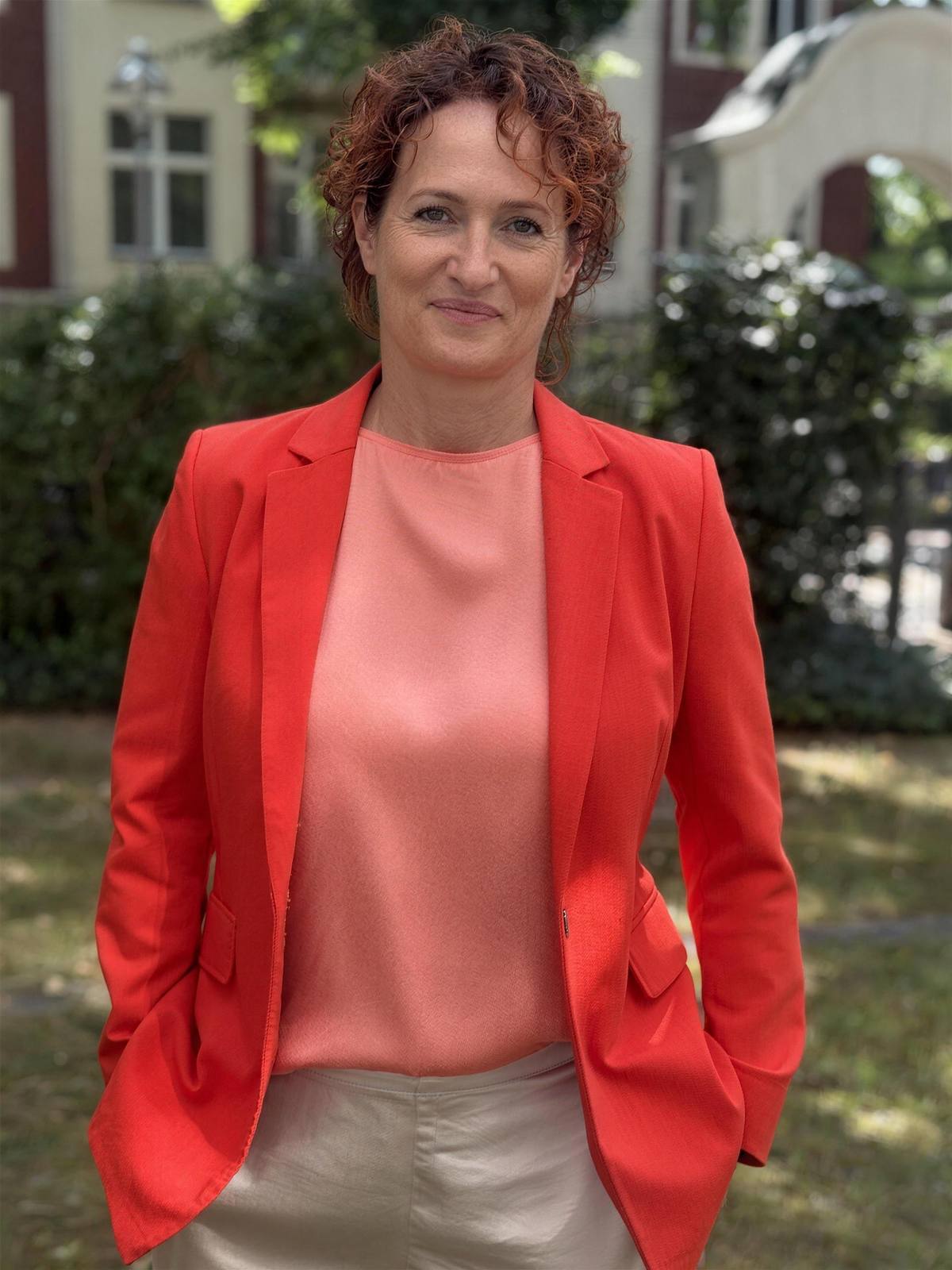 Jenny Völker im roten Blazer vor ihrer Praxis-Villa in Berlin-Zehlendorf